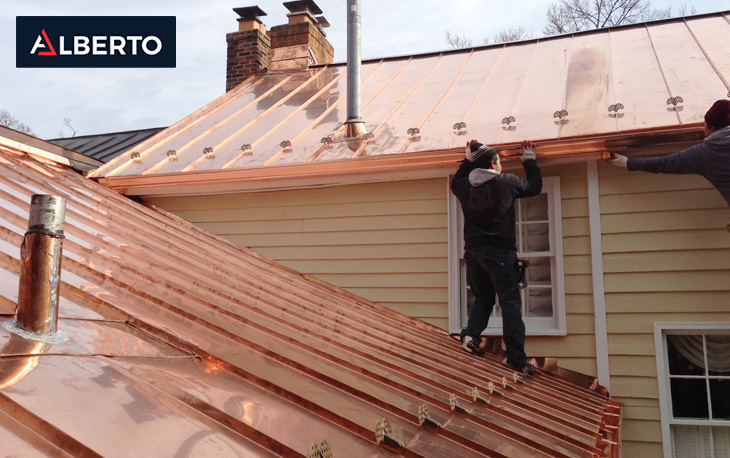 Contractors installing copper roofing panels on a building.